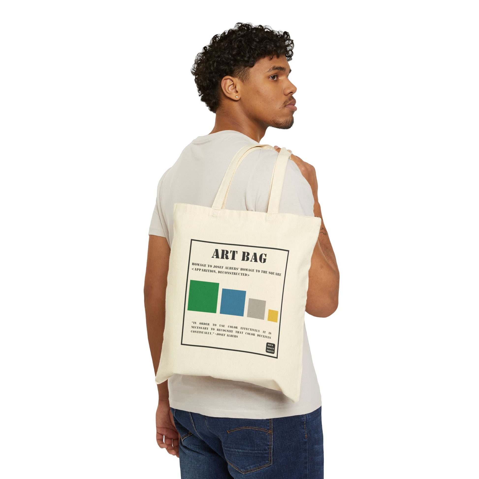 Image of a man holding a cotton canvas tote over his shoulder printed with large-text words "Art Bag," smaller text saying "Homage to Josef Albers' Homage to the Square (Apparition, Deconstructed) above four colored squares and a quote by the artist Josef Albers on color.